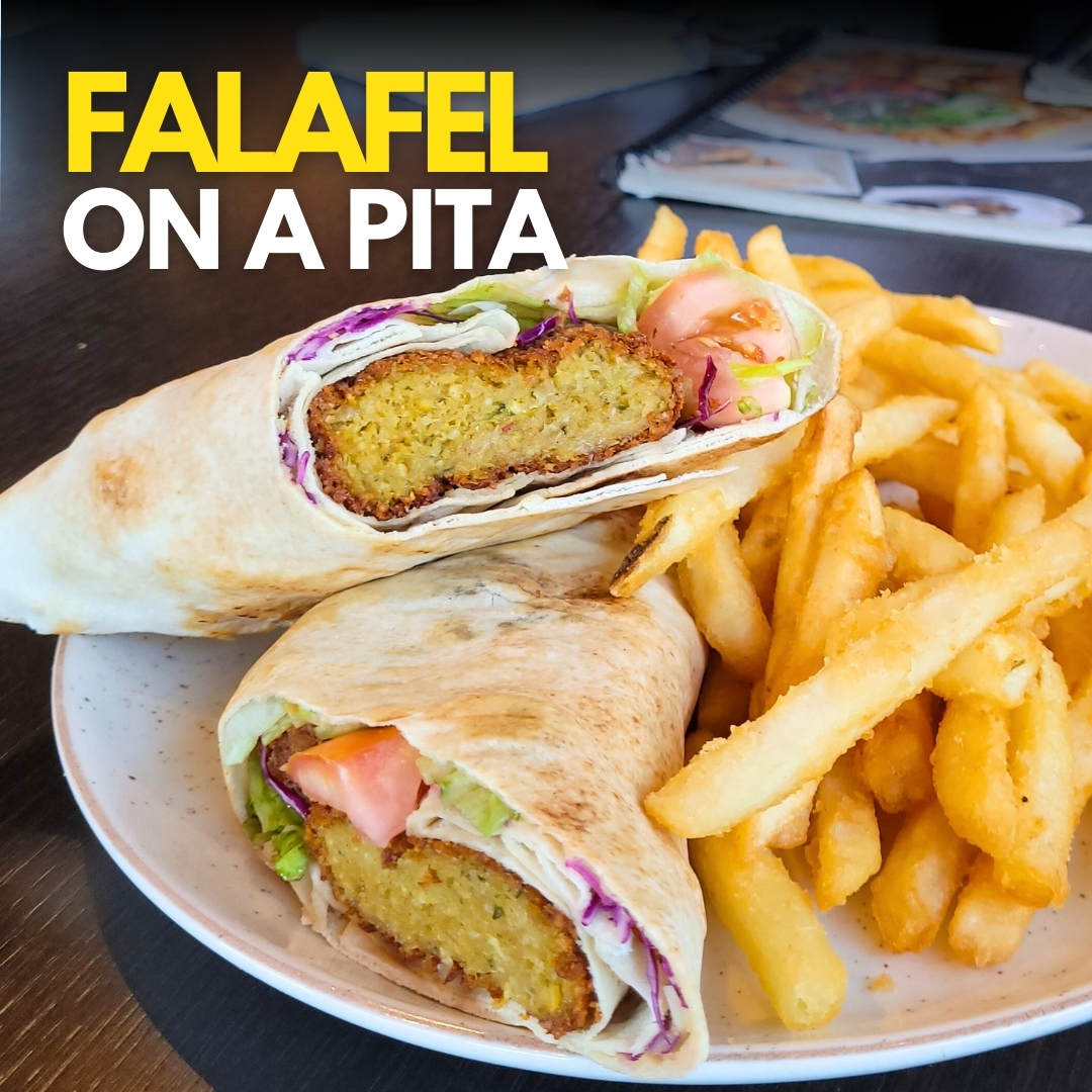 Falafel pita wraps served with French fries on a white plate.