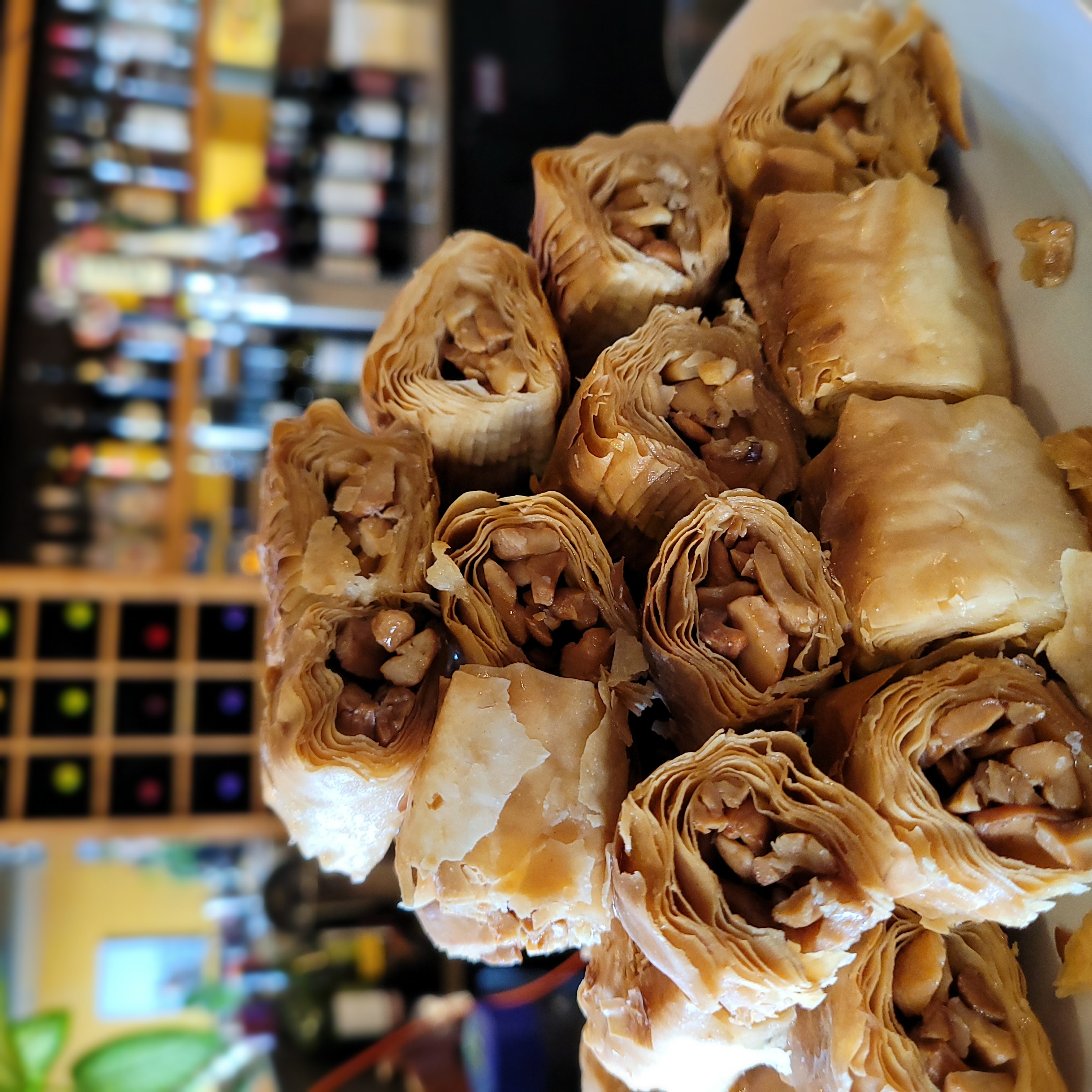 Plate stacked with pieces of rolled baklava filled with chopped nuts in a restaurant setting.