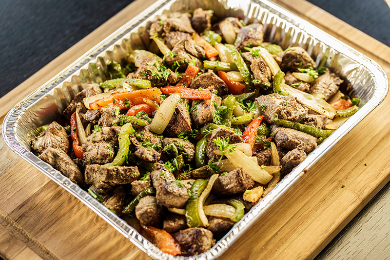 Tray of seasoned lamb shashlik with green and red bell peppers and onions garnished with fresh parsley.
